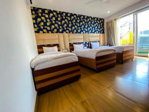 two beds in a room with wooden floors at Sky Suites in Gurgaon