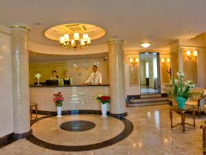 um lobby de um hotel com duas pessoas em pé em um balcão em Alleya Grand em Poltava
