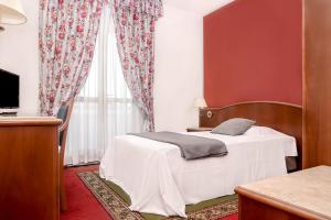 a bedroom with a white bed and a window at Hotel Poli in Castelnovo di Sotto