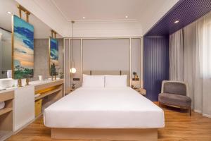 ein Schlafzimmer mit einem großen weißen Bett und einem Stuhl in der Unterkunft Marco Polo Hotel in Phnom Penh