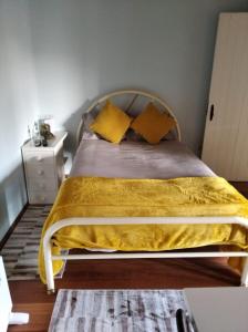 uma cama com cobertores amarelos e almofadas num quarto em Quinta dos Campos - Apartamento 2 em Braga