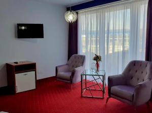 ein Wohnzimmer mit zwei Stühlen, einem Tisch und einem Fernseher in der Unterkunft Hotel SunGarden Salin in Turda
