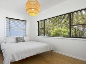 Un dormitorio con una cama en una habitación con ventanas. en Bellevue, en Culburra Beach