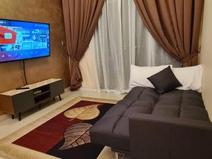 a living room with a couch and a flat screen tv at Eid SKS Habitat -Free Wifi Netflix, Larkin, Johor Bahru in Johor Bahru