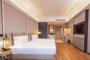 a bedroom with a large white bed and a kitchen at Marco Polo Hotel in Phnom Penh