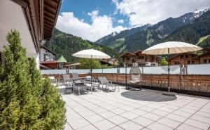 um pátio com cadeiras e guarda-sóis num edifício em Hotel Viktoria & Landhaus Joggl em Mayrhofen
