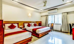 a hotel room with two beds and a window at Hotel U.T.Elegance in Bangalore