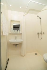 uma casa de banho branca com um lavatório e um chuveiro em Szobi Malomkert Lovarda em Szob