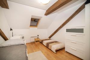 1 dormitorio en el ático con 1 cama y TV en Szobi Malomkert Lovarda en Szob