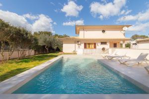 a villa with a swimming pool in front of a house at Calma in Son Serra de Marina