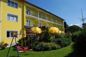 ein Apartmenthaus mit einem Spielplatz davor in der Unterkunft Pension Agnes in Sankt Kanzian am Klopeiner See