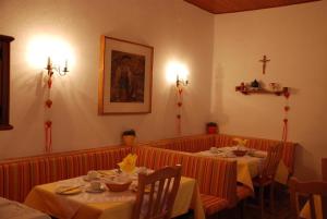 ein Esszimmer mit 2 Tischen und einem Kreuz an der Wand in der Unterkunft Pension Agnes in Sankt Kanzian am Klopeiner See