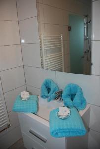 La salle de bains est pourvue d'un lavabo, de serviettes bleues et d'un miroir. dans l'établissement Pension Agnes, à Sankt Kanzian