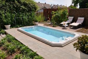 a swimming pool in a yard with two chairs at B&B De Joker in Turnhout