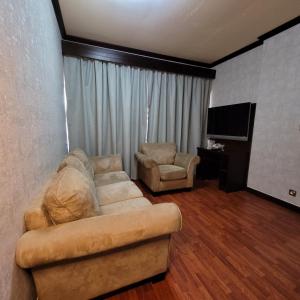 a living room with a couch and a television at Strand Hotel in Abu Dhabi