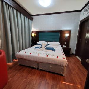 a bedroom with a large bed with a blue headboard at Strand Hotel in Abu Dhabi