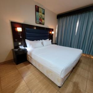 1 dormitorio con 1 cama blanca grande y cabecero azul en Strand Hotel, en Abu Dabi