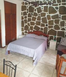 - une chambre avec un lit et un mur en pierre dans l'établissement Mountain Apartments x4, à Anse Etoile