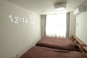 TKD HOUSE Asahikawa في اساهيكاو: غرفة نوم بسريرين وساعة على الحائط