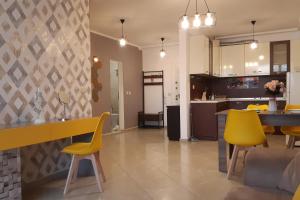 a kitchen and living room with yellow chairs and a table at Апартамент Адикт in Sozopol