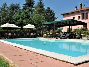 a swimming pool with chairs and umbrellas next to a house at Agriturismo La Prosciutta in Faenza