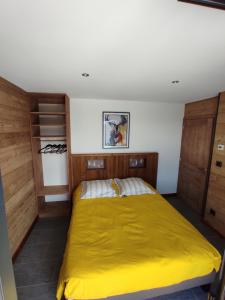 - une chambre avec un lit jaune et des placards en bois dans l'établissement Nature Cottage Vosges Spa Le Cerf, à Anould