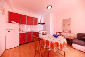 kuchnia ze stołem i kuchnia z czerwonymi szafkami w obiekcie Apartments Melita w mieście Zadar