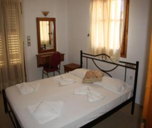 バリにあるDimitris Apartmentsのベッドルーム1室(白いシーツと鏡付きのベッド1台付)