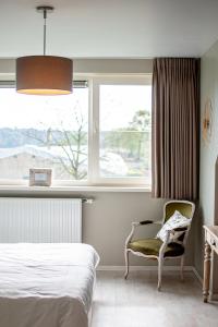 a bedroom with a bed and a chair and a window at B&B Tuin der Zinnen in Rijkevorsel