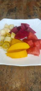a white plate with fruits and vegetables on a table at Sweet Time Bungalows in Koh Rong Sanloem