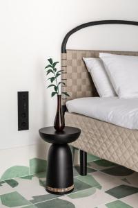 Concepcio by Nobis, Palma, a Member of Design Hotels في بالما دي ميورقة: وجود مزهرية على طاولة بجانب سرير