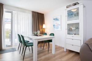 une salle à manger blanche avec une table blanche et des chaises vertes dans l'établissement Memelstraße 7 Strandgut, à Dahme