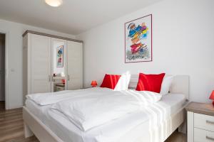 - une chambre blanche avec un grand lit blanc et des oreillers rouges dans l'établissement Memelstraße 7 Strandgut, à Dahme