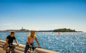 a man and a woman riding bikes next to the water at Maistra Camping Amarin Glamping in Rovinj +44 photos