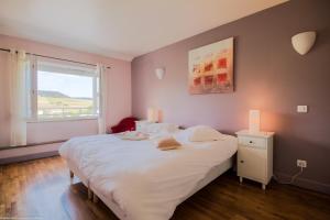 a bedroom with a large white bed and a window at Les Meix sous le Château in Meursault