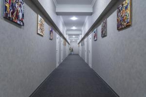 un couloir avec un long couloir orné de peintures sur les murs dans l'établissement THE TIME HOTEL, à Tachkent