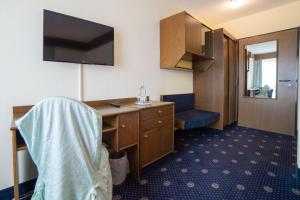 a room with a desk and a tv on the wall at City Club Hotel in Oldenburg