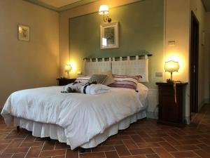 アレッツォにあるラ カンティーナ ルレ ファットリーア イル チプレッソのベッドルーム(白い大型ベッド、ランプ2つ付)