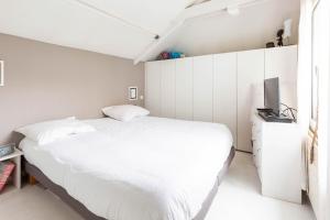 Schlafzimmer mit einem weißen Bett und einem TV in der Unterkunft Veeve - White House in Paris