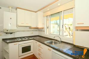 een keuken met witte kasten, een wastafel en een raam bij Casa Adela in Roda de Bará