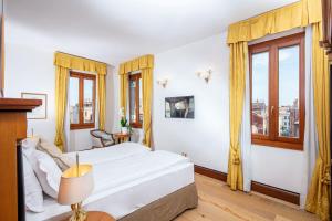 a bedroom with a bed and two windows at All’Angelo Art Hotel in Venice