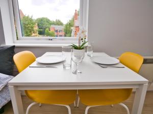een witte eettafel met gele stoelen en een raam bij Stunning property fully refurbished in Birmingham