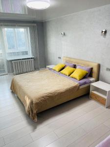 a bedroom with a large bed with yellow and purple pillows at Апартаменты LUX в центре. Ярослава Мудрого 72 (97й квартал) in Kryvyi Rih