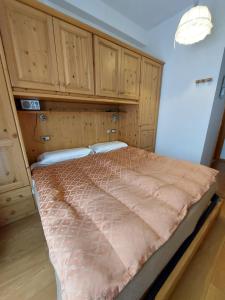 Bett in einem Zimmer mit Holzschränken in der Unterkunft Hotel Montana- ricarica auto elettriche in Cortina d'Ampezzo