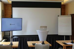 sala prezentacyjna z dwoma stołami i dużym ekranem w obiekcie Hotel Sankt Georg w mieście Neubrandenburg