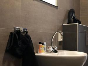 ein Badezimmer mit einem Waschbecken und einer schwarzen Tasche daneben in der Unterkunft BnB Grand Café Prins Bernhard in Venlo