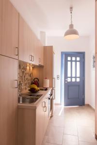 uma cozinha com armários de madeira e uma porta azul em BLUE Seaside Studio em Sifnos