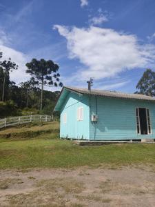 a blue house in a field next to a fence at Recanto do Physalis in Rio Rufino