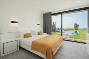 a bedroom with a bed and a view of a pool at Modern villa pool garden seaview Ocean Sunset in Caniço +16 photos