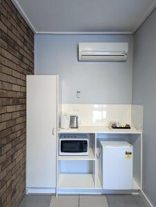 a white kitchen with a microwave and a refrigerator at Homestead Motor Inn & Apartments in Bendigo